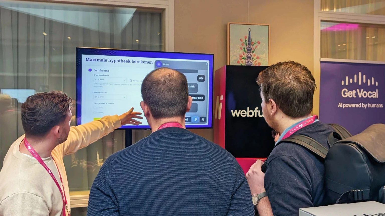 Three people discuss a mortgage calculator on a display beside Webfuse and Get Vocal banners.